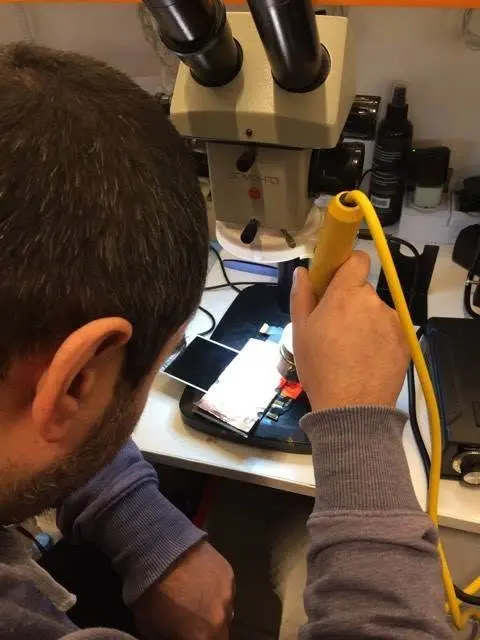 Tehnician Kubifix reparând un telefon la microscop